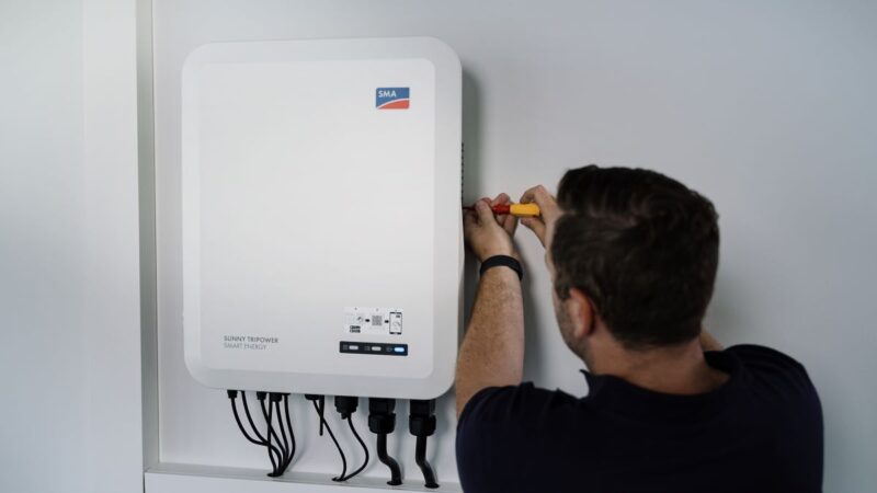 Ein Installateuer montiert SMA-Wechselrichter Sunny Tripower Smart Energy