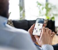 Ein Mann betrachtet sein Mobiltelefon, das eine PV-Appöiaktion anzeigt.