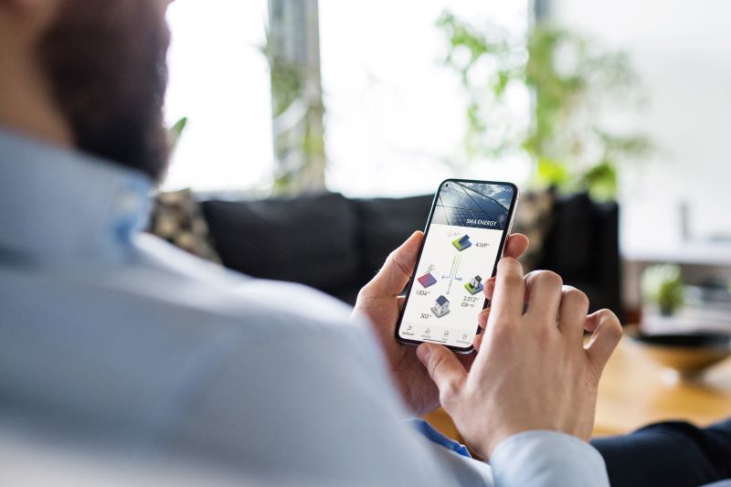 Ein Mann betrachtet sein Mobiltelefon, das eine PV-Appöiaktion anzeigt.