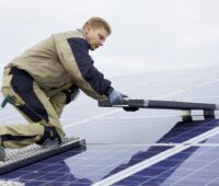 Zu sehen ist ein Monteur. Er verlegt die mobile Photovoltaik-Arbeitsplattform.