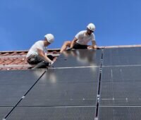 Zwei Monteure von PV-Modulen auf einem Einfamilien-Schrägdach.