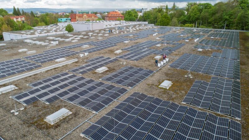 Luftaufnahem eines großen Flachdachs mit Photovoltaik und zwei Personen.