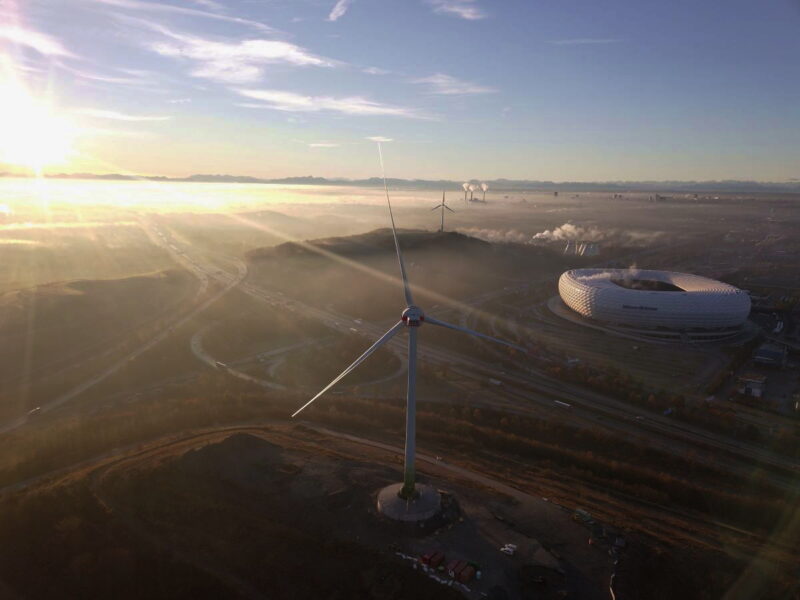 Luftbild mit Windenergie, der Allianz-Arena und Wolken über der Landschaft.