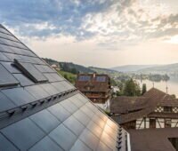 Eine dachintegrierte PV-Anlage in einem Dorf an einem Schweizer Bergsee.