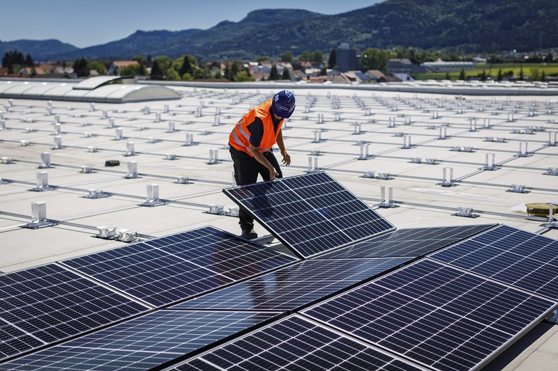 Zu sehen ist ein Arbeiter auf einem Flachdach bei der Montage von PV-Modulen mit dem Photovoltaik-Montagesystem MSP von Schweizer.