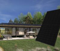 Im Bild eine Montage aus Gebäude mit PV-Dach und im Vordergrund ein schwarzes Photovoltaik-Modul von Sharp.