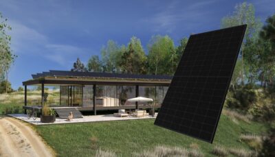 Im Bild eine Montage aus Gebäude mit PV-Dach und im Vordergrund ein schwarzes Photovoltaik-Modul von Sharp.