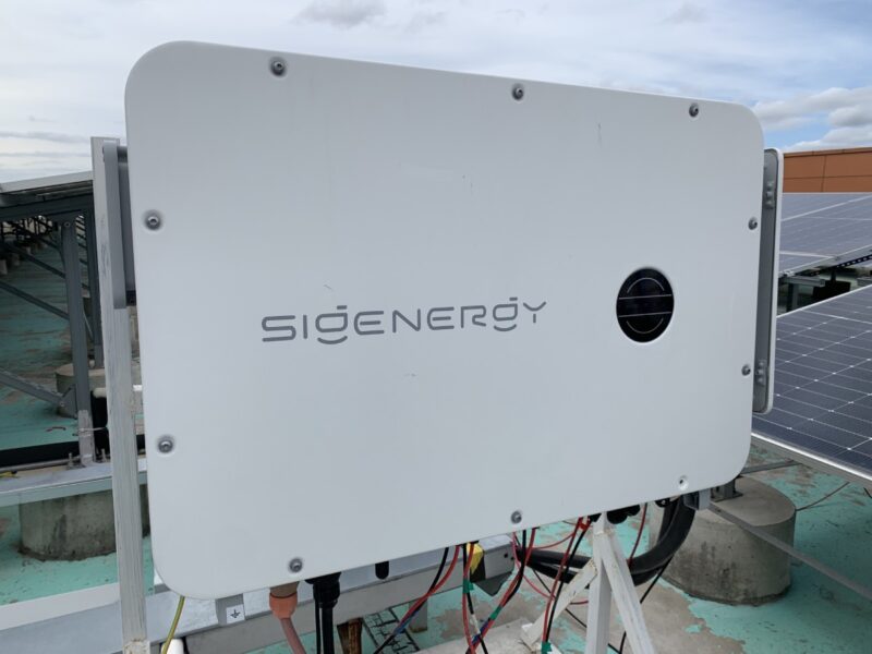 Wechselrichter von Sigenergy neben PV-Modulen.