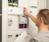 Person an einem Schaltschrank mit smart meter.