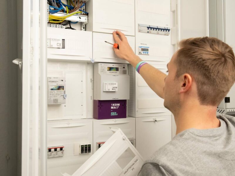 Person an einem Schaltschrank mit smart meter.