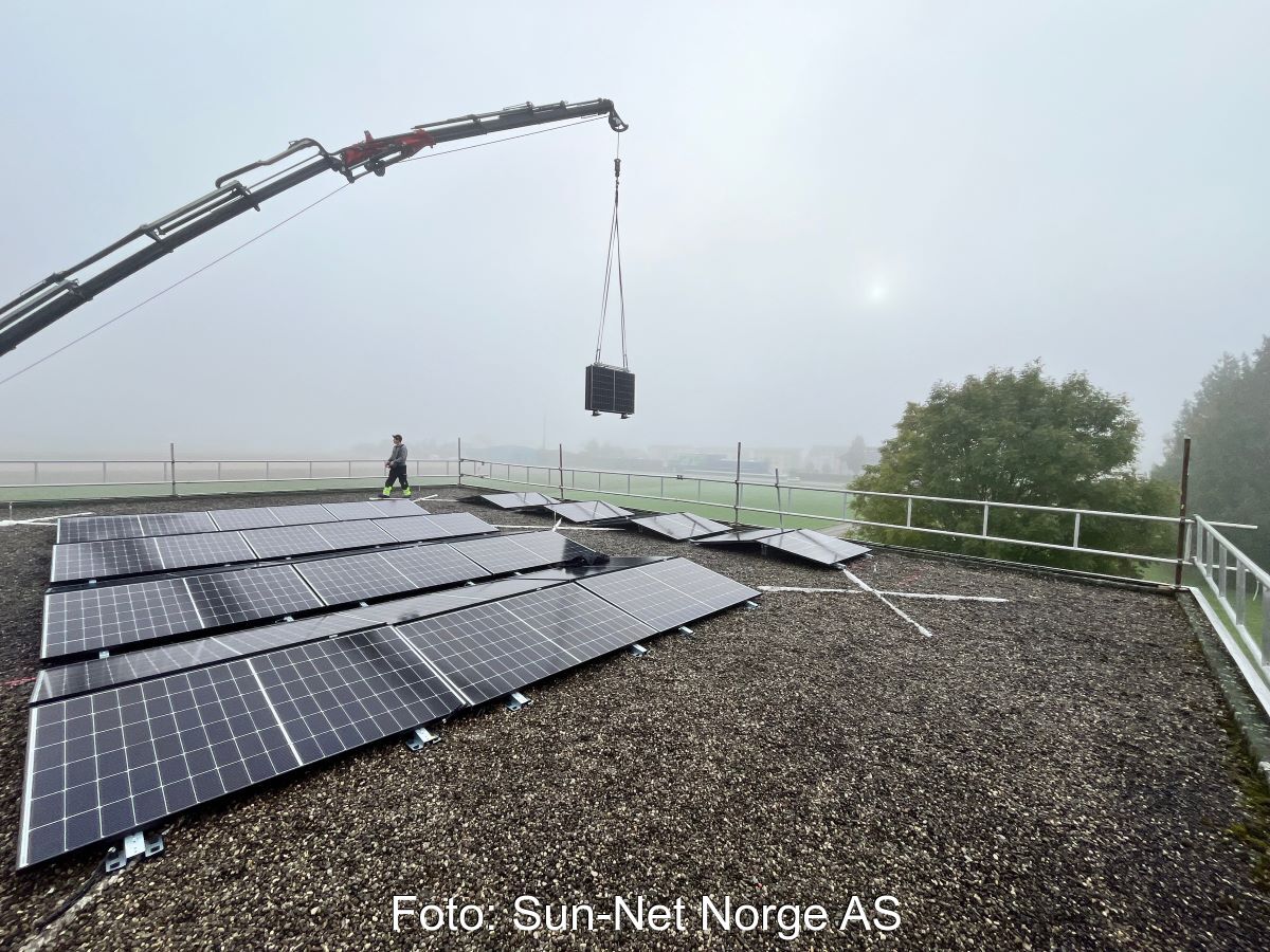 Ein Kran hebt faltbare PV-Module auf ein Flachdach.
