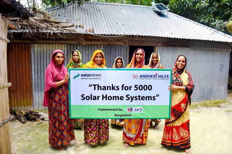 Frauen aus Bangladesch vor Haus mit Solarhome-System.