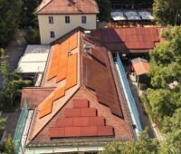 Kupferrote Solarmodule auf einem Dach mit Bieberschwanzschindelnim Englischen Garten Münchens.