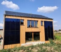 Ein freistehendes Haus, das Solarthermie, PV, Stroh und Holz nutzt.