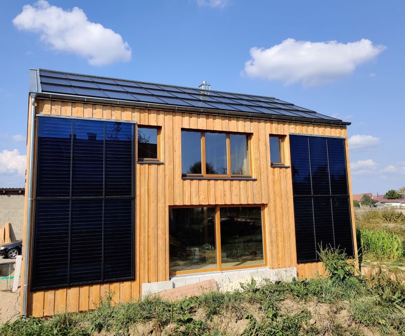 Ein freistehendes Haus, das Solarthermie, PV, Stroh und Holz nutzt.