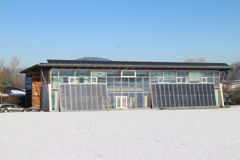 Ein Flachbau au schneebedecktem Boden und Sonnenkollektoren an der Fassade.