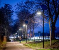 Ein Radweg in der Dämmerung mit Straßenbeleuchtung.