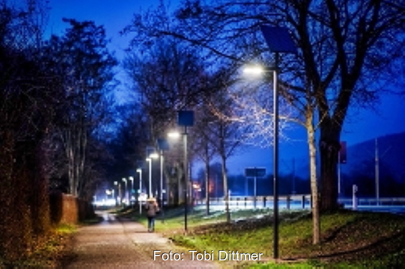 Ein Radweg in der Dämmerung mit Straßenbeleuchtung.