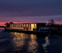 Ein Katamaran auf der Spree, beleuchtet zum späten Sonnenuntergang.
