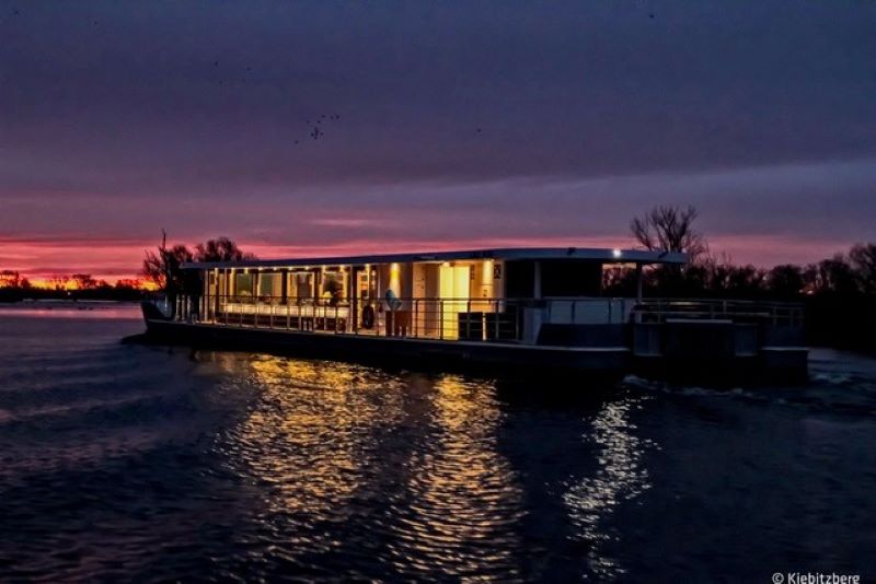 Ein Katamaran auf der Spree, beleuchtet zum späten Sonnenuntergang.