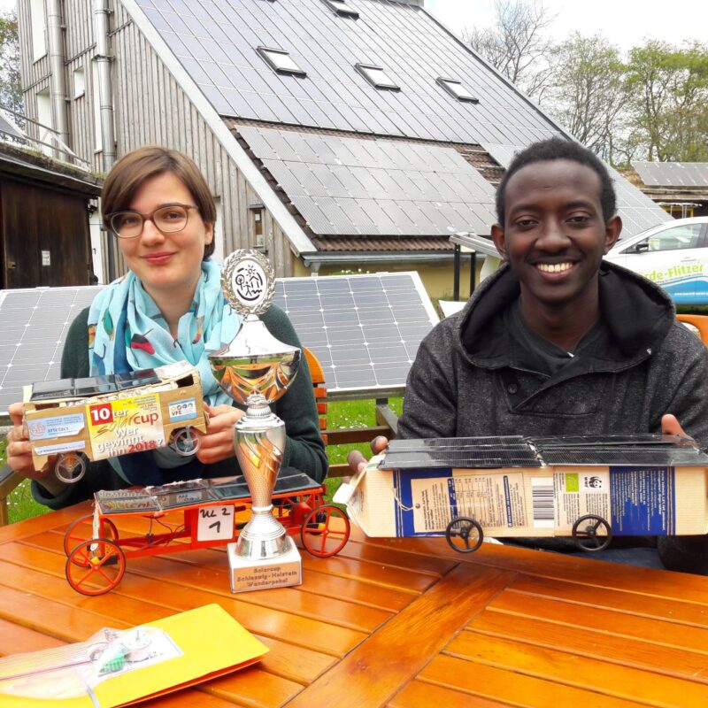 Ein Mädchen und ein Junge präsentieren ihre selbstgebastelten Solarfahrzeuge