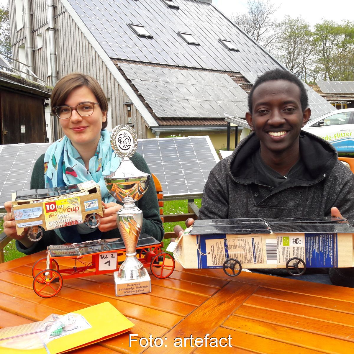 Ein Mädchen und ein Junge präsentieren ihre selbstgebastelten Solarfahrzeuge