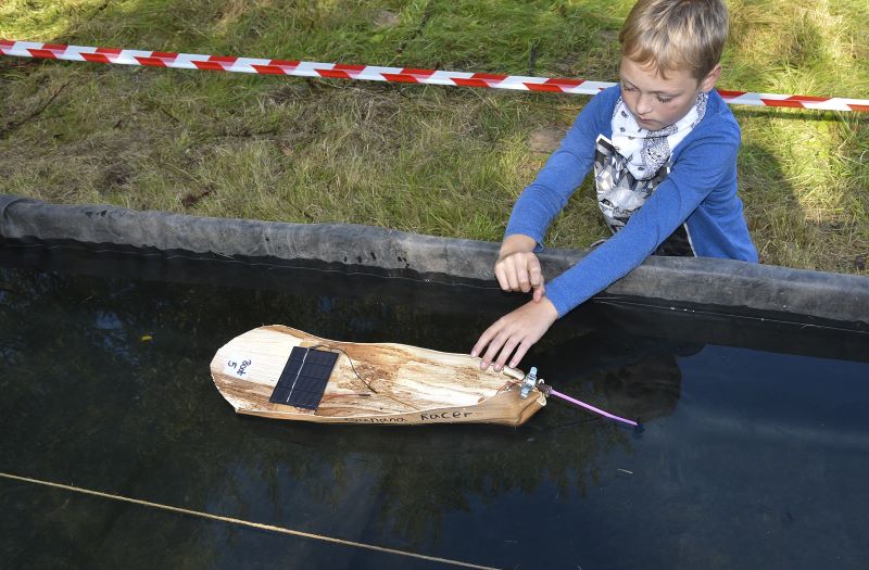 Ein Junge mit einem selbst gebauten Solarboot aus Bananenblättern.