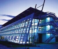 Eine bei Nacht im blauen Licht leuchtende Fassade eines Industriegebäudes: der ersten Solar-Fabrik in Freiburg.