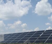 Freifeldsolaranlage unter blassblauem Himmel mit Wolken