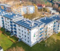 Ein größeres Mehrfamilienhaus auf einer Wiese. Auf dem Photovoltaikanlagen