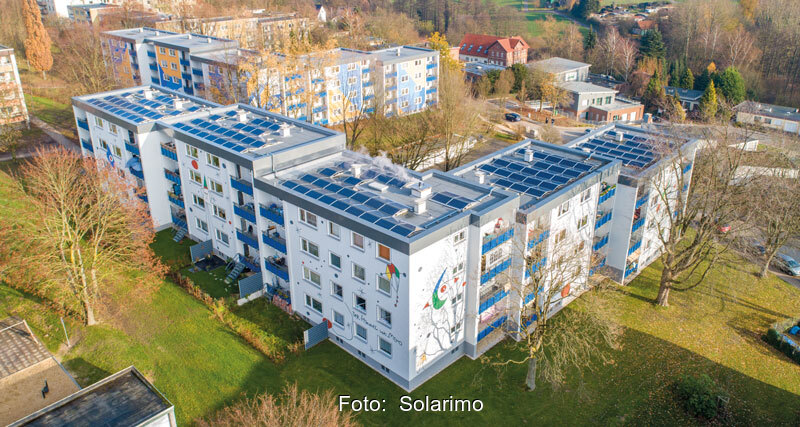 Ein größeres Mehrfamilienhaus auf einer Wiese. Auf dem Photovoltaikanlagen