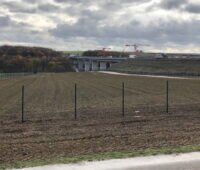 Ein Feld am Rande einer Autobahnbrücke.