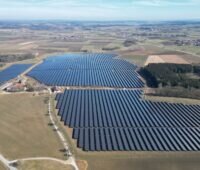 Luftbild eines Freiflächen-Solarparks auf eher braunen Wiesen.
