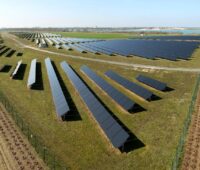 Ein Freiflächensolarpark im Flachland am Rande eines kleinen Binnengewässers.