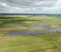 Luftbild eines Solarparks in Wiesen- und Ackerumfeld im Flachland.