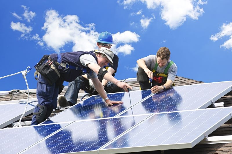 Zu sehen sind drei Handwerker beim Installieren einer Photovoltaik-Anlage. Die Verbraucherzentrale hat ein Positionspapier zur Solarpflicht vorgelegt.