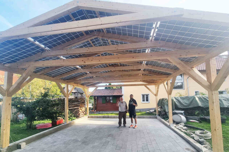 Zu sehen ist ein PV- Carport aus Holz mit semitransparenten Doppelglasmodulen.