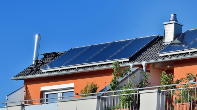 Foto einer Solarthermie-Anlage auf einem Wohnhaus vor blauem Himmel.