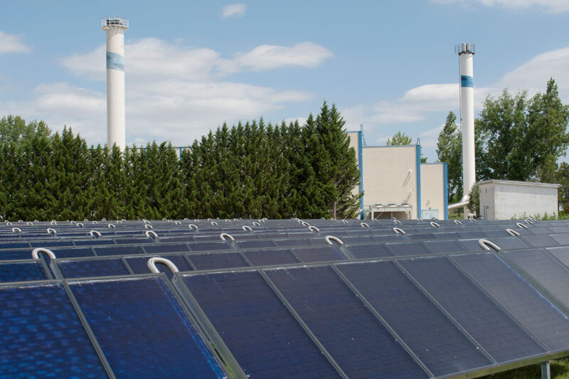 Solarthermieanlage in Vordergrund, Fernwärme-Heizkraftwerk Bernburg im Hintergrund - Symbolbild für BEW-Förderung
