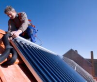 Ein Monteur installiert einen Solarwärmekollektor auf dem Dach.