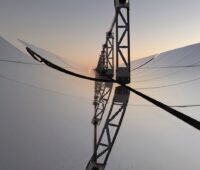 Ansicht auf die Spiegel eines Parabolrinnenkraftwerks mit gebogenen Spiegeln, die das Licht auf ein Rohr im Brennpunkt reflektieren. Zuwachs bei Solarthermie kann auch durch solche Anlagen erfolgen.