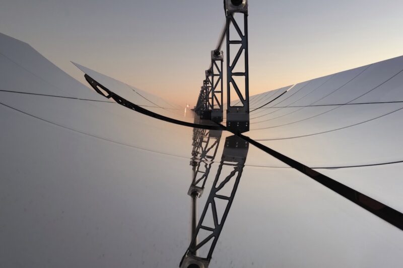 Ansicht auf die Spiegel eines Parabolrinnenkraftwerks mit gebogenen Spiegeln, die das Licht auf ein Rohr im Brennpunkt reflektieren. Zuwachs bei Solarthermie kann auch durch solche Anlagen erfolgen.