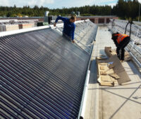 Montage eienes großen Solarkollektors auf einem Fabrikdach.