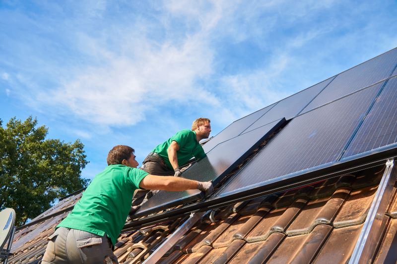Arbeiter installieren auf einem Spitzdach neue Solarstrommodule.
