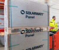 Verpackte Solarmodule von Solarwatt auf einer Palette im Lager mit Arbeitern.