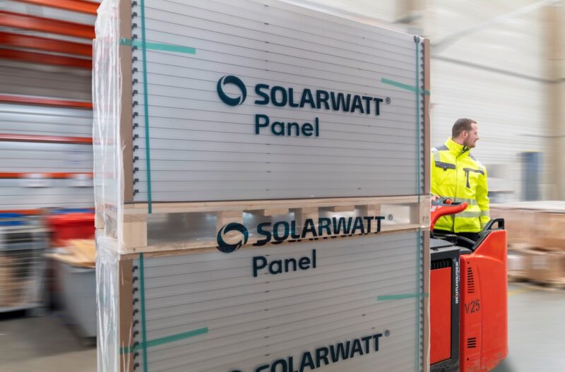 Verpackte Solarmodule von Solarwatt auf einer Palette im Lager mit Arbeitern.