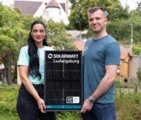 Eine Frau und ein Mann halten ein kleines Solarmodul mit dem Schriftzug Solarwatt Ludwigsburg.