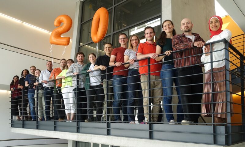 Die Mitarbeiter:innen von Solites in einer Reihe mit 20 Jahre Luftballons, Wärmenetze sind der Schwerpunkt des Instituts.