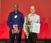 Zwei Personen auf einer Bühne empfangen Ehrungen zum Gewinn des Innovationspreises Berlin Brandeburg 2025.