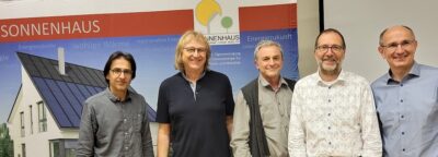 Fünf Männer vor Plakat mit Sonnenhaus-Institut.